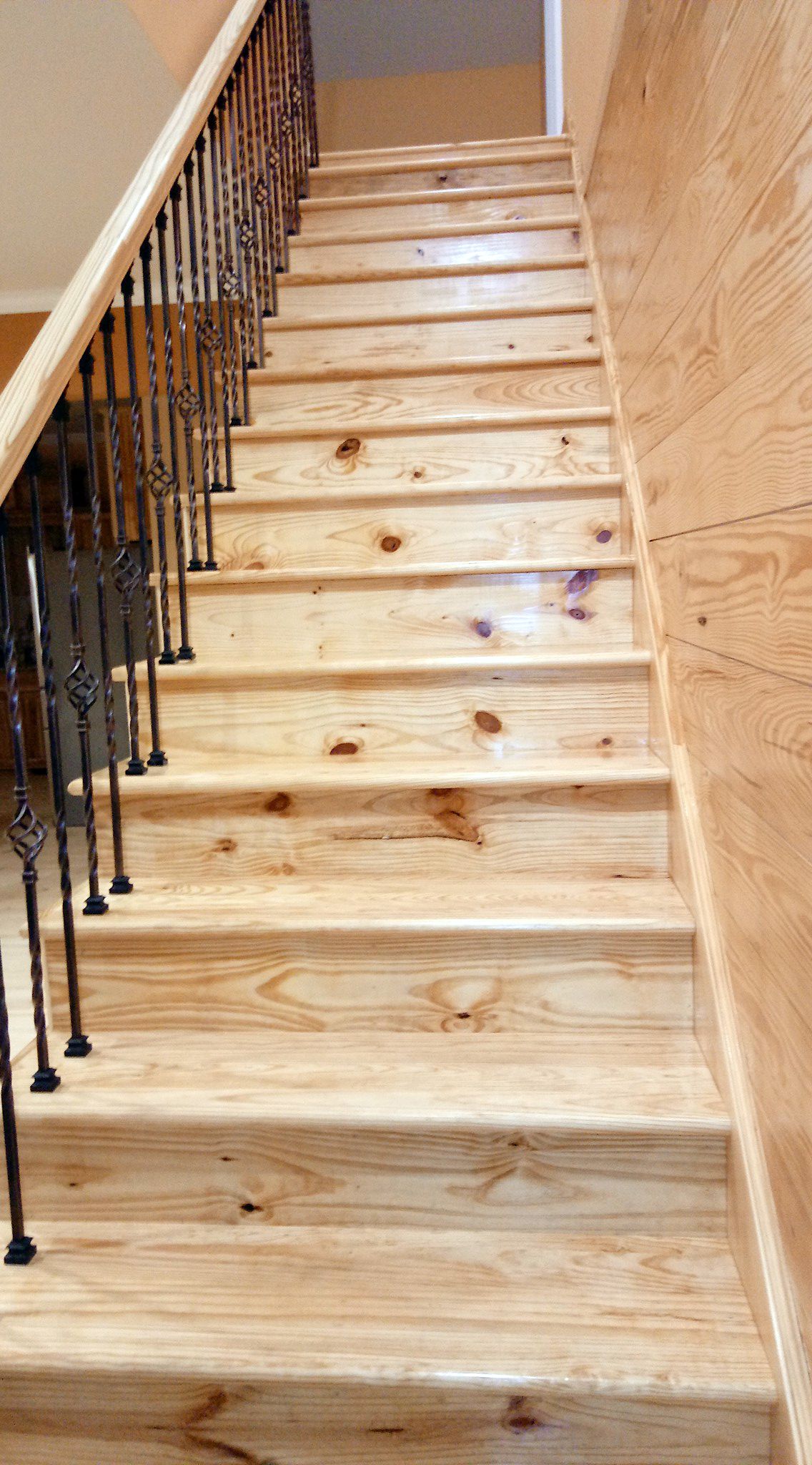 A wooden staircase with a wrought iron railing leading up to the second floor.