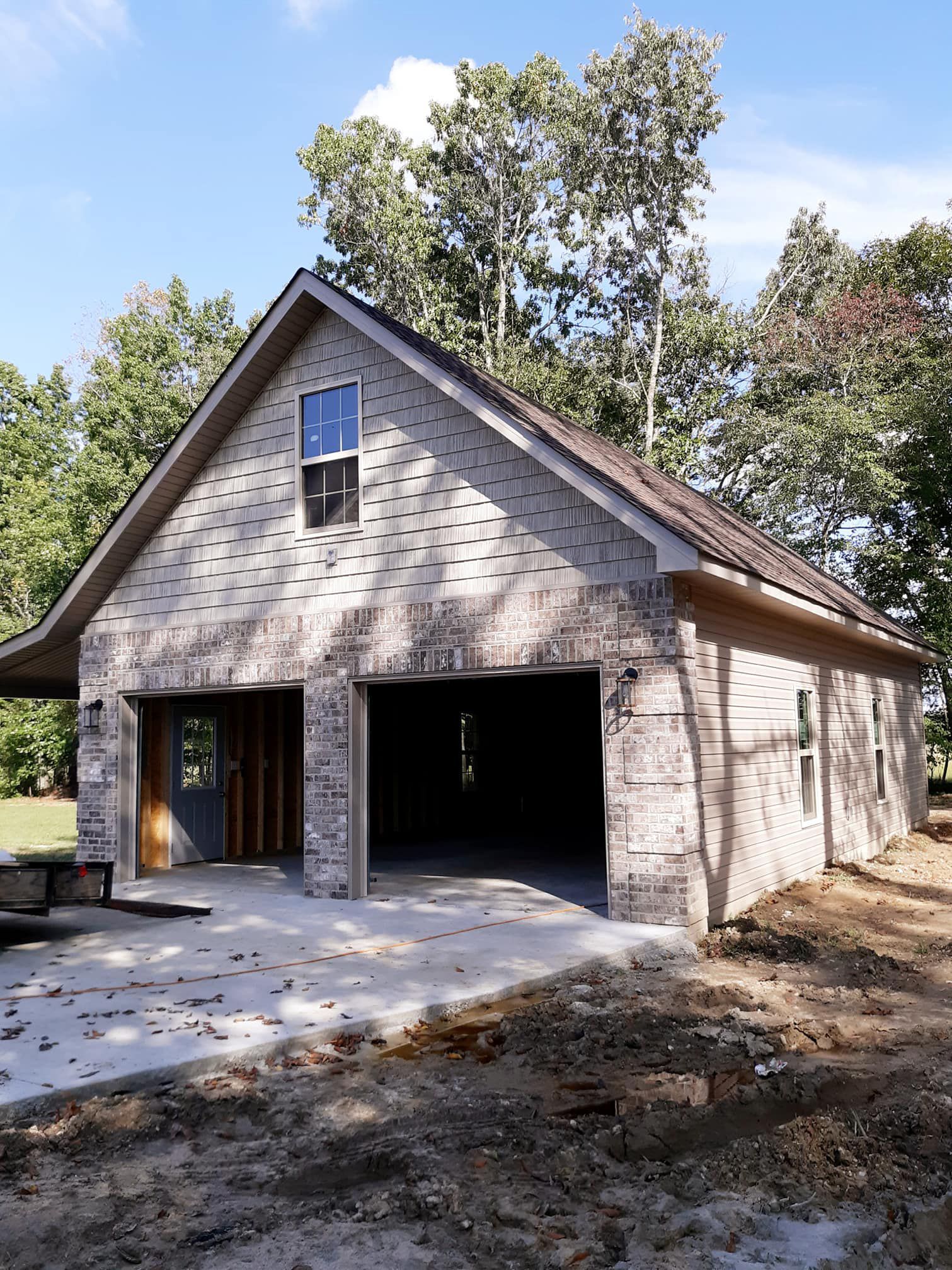 A brick garage with a roof that is covered in shingles