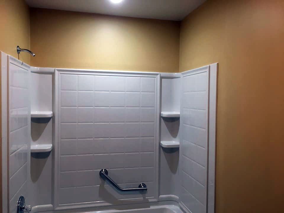 A bathroom with a bathtub , shower , and shelves.