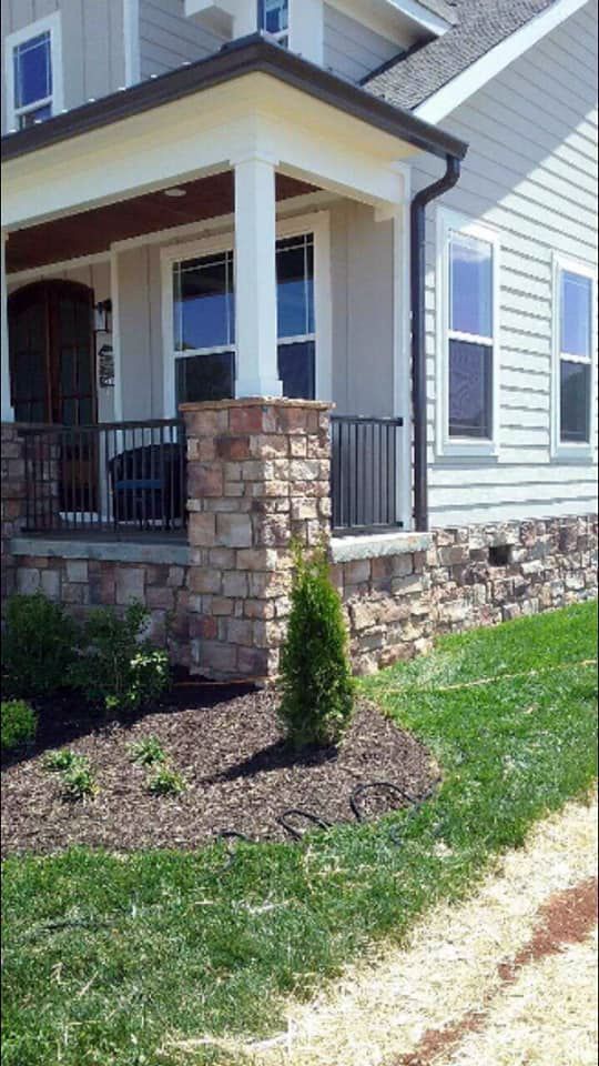 A house with a porch and a stone wall