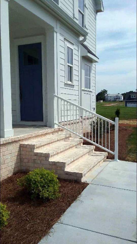 A white house with a blue door and stairs leading up to it.