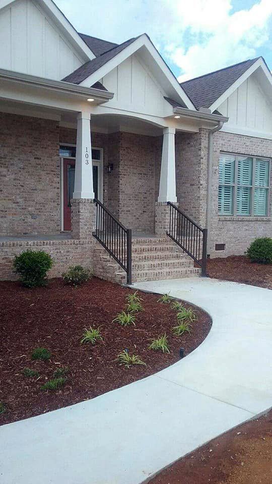 A brick house with a concrete walkway leading to the front door.