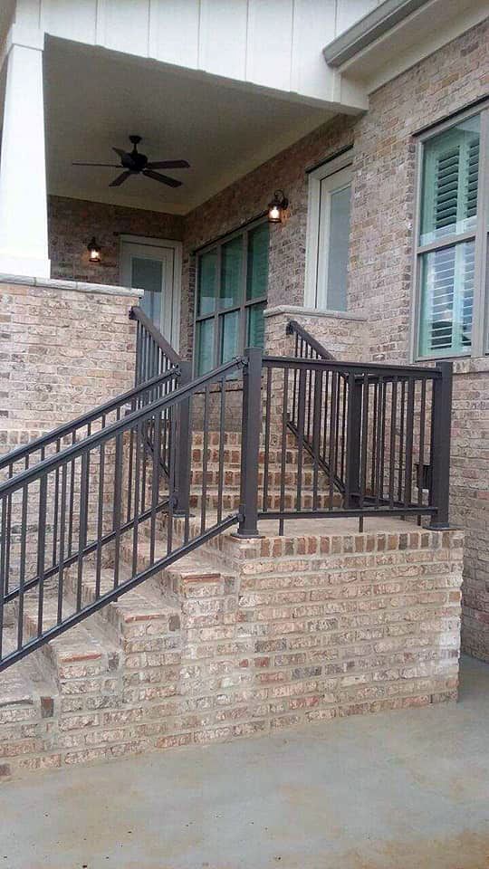 A brick building with stairs and a metal railing.