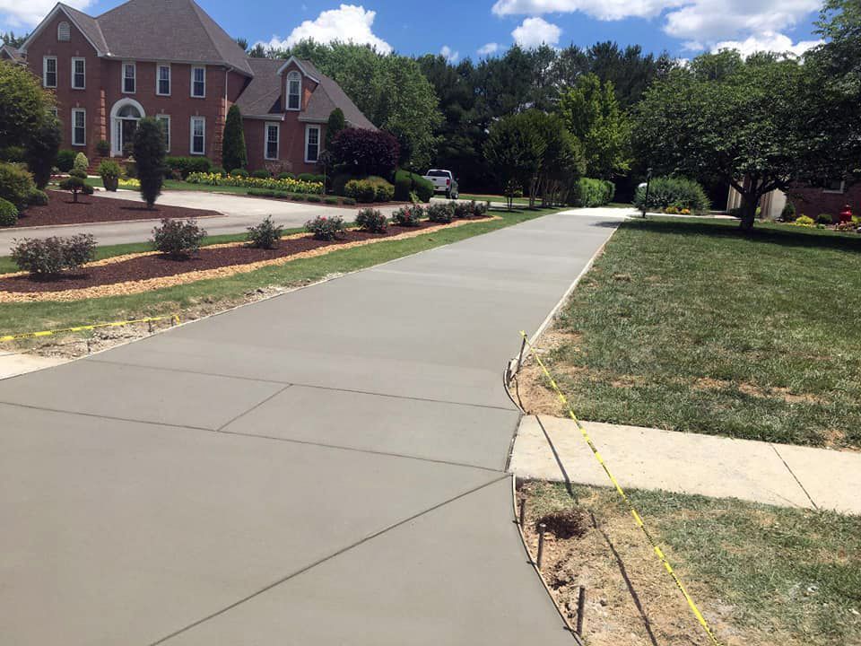 A concrete driveway is being built in front of a large house