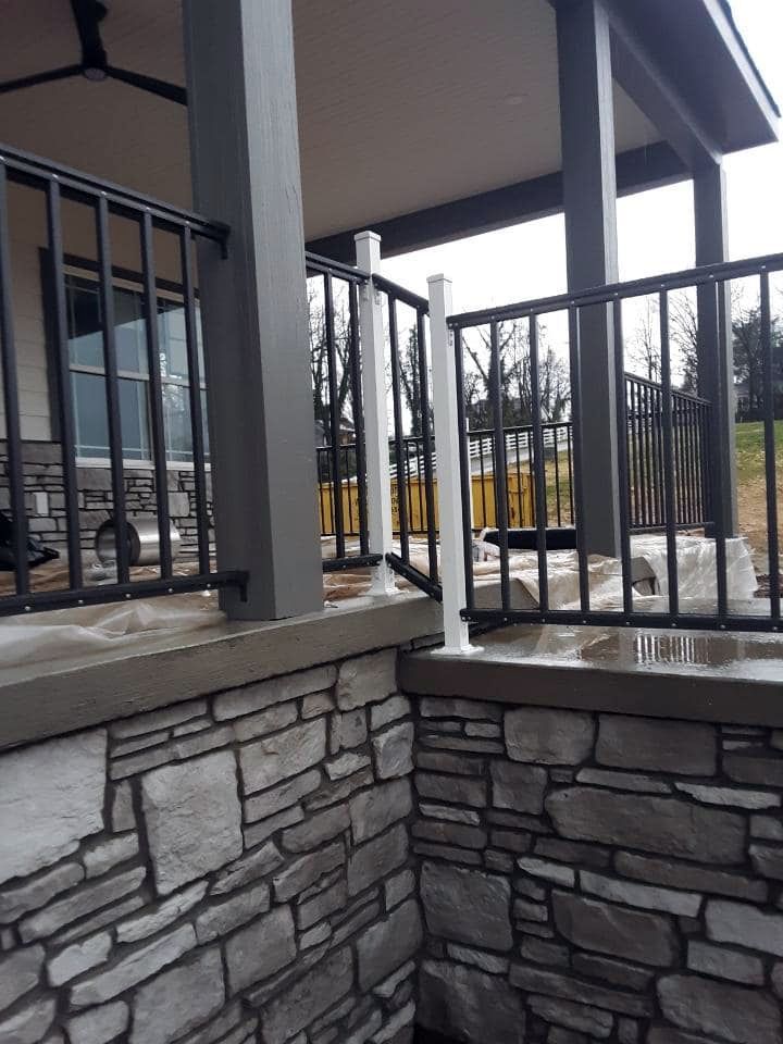 A porch with a stone wall and a metal railing