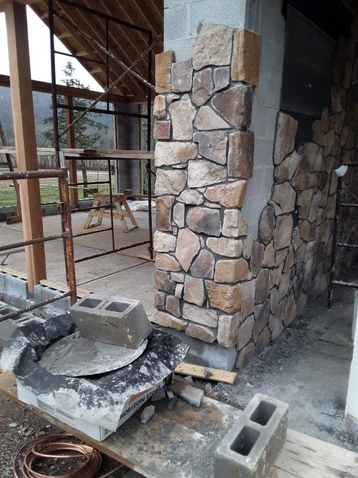 A stone wall is being built in a building with scaffolding.