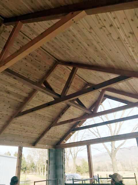 A man is standing under a wooden roof.