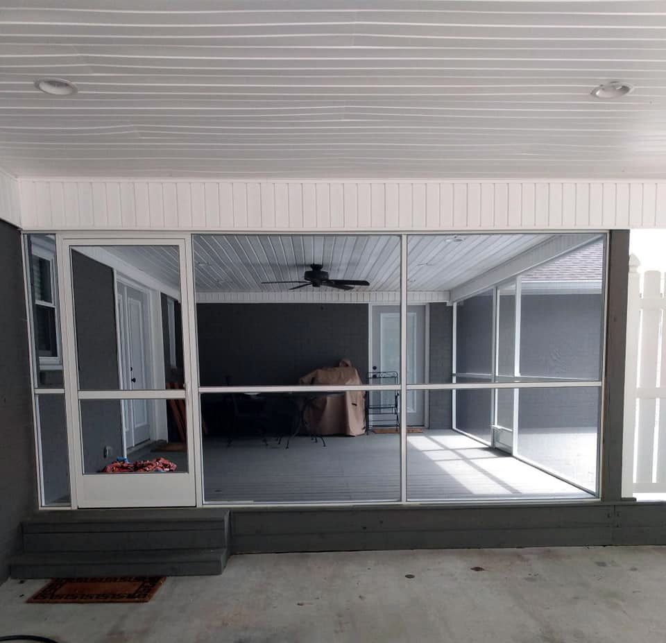 A screened in porch with a lot of windows and a ceiling fan.
