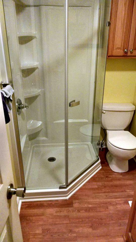 A bathroom with a toilet , shower and glass door.