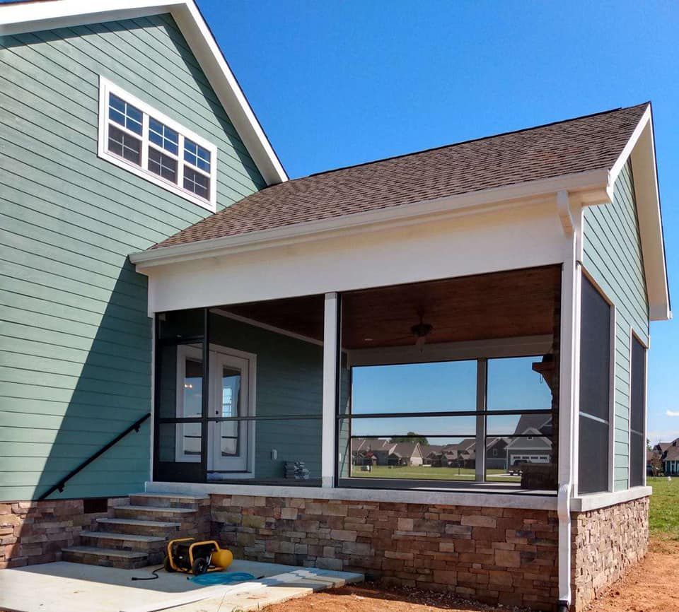 A green house with a screened in porch and stairs