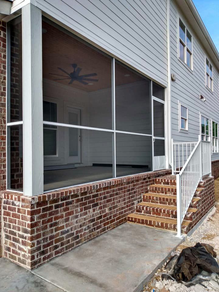 A screened in porch with stairs and a ceiling fan on the side of a house.
