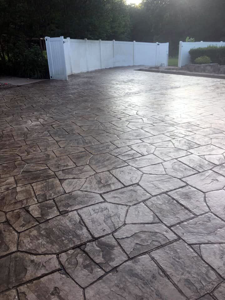 A brick driveway with a white fence in the background