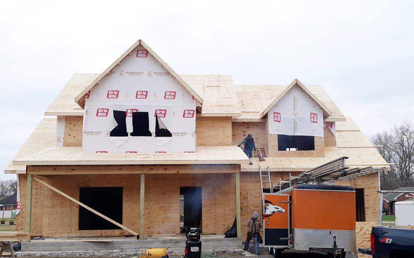 A house is being built with a truck parked in front of it.