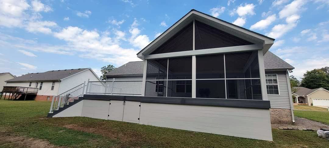 The back of a house with a screened in porch and stairs.