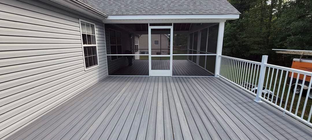 A screened in porch with a wooden deck and a white railing.