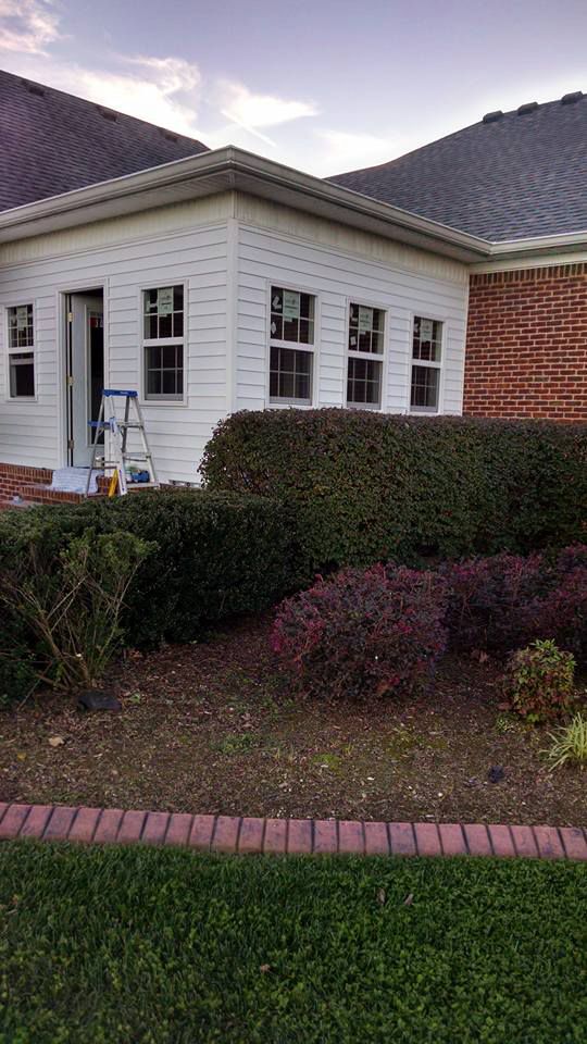 A white house with a ladder in front of it is being painted.