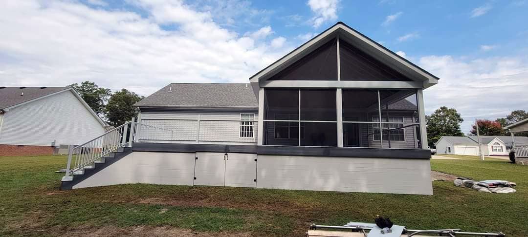 The back of a house with a screened in porch and stairs.