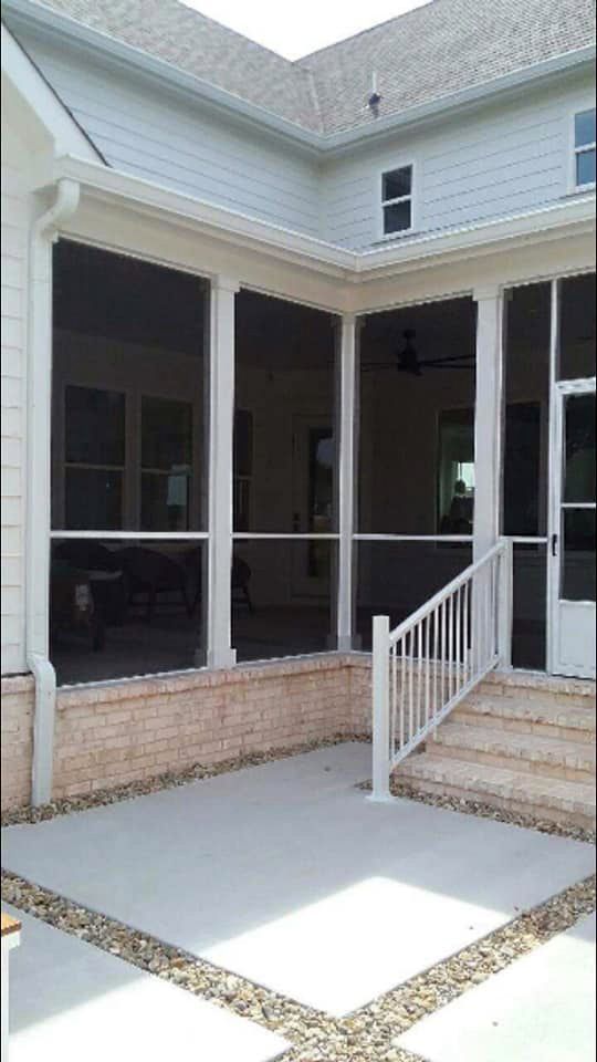 A screened in porch with a white railing and stairs