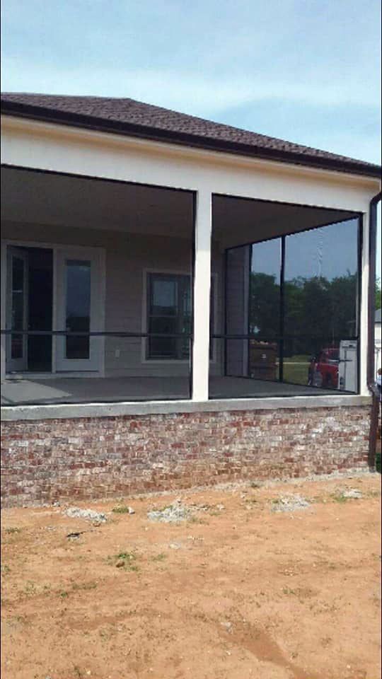 A house with a screened in porch and a brick wall.