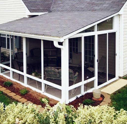 A screened in porch with a roof and lots of windows