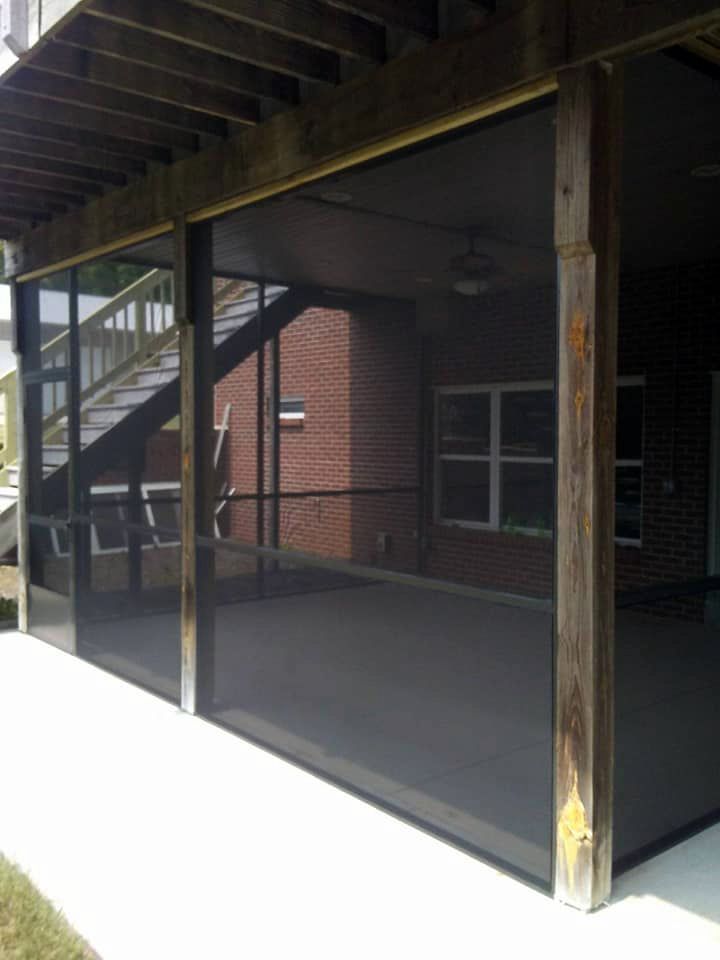 A screened in porch with a brick house in the background