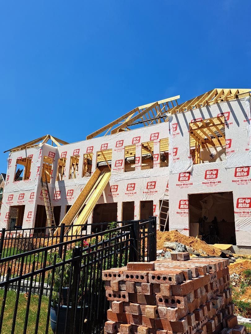 A large house is being built with bricks in front of it.