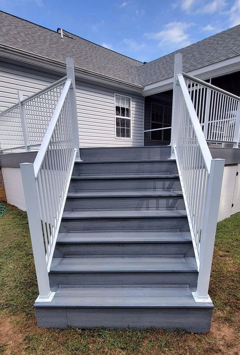A set of stairs leading up to a deck with a white railing.