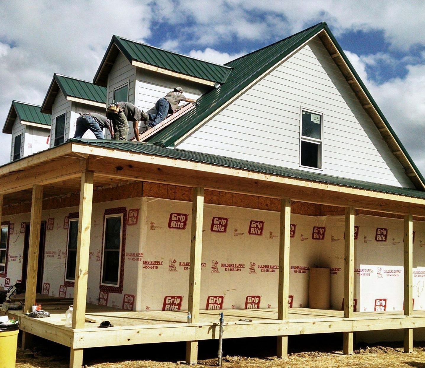 A white house with a green roof is being built