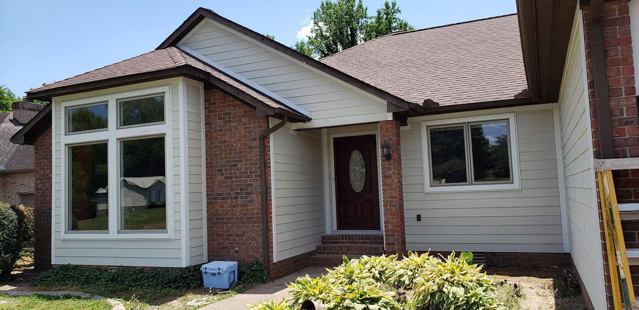 A white house with a red door and a ladder in front of it.