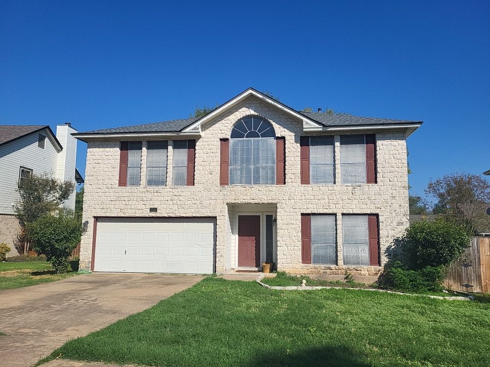 A large brick house with a white garage door and red shutters