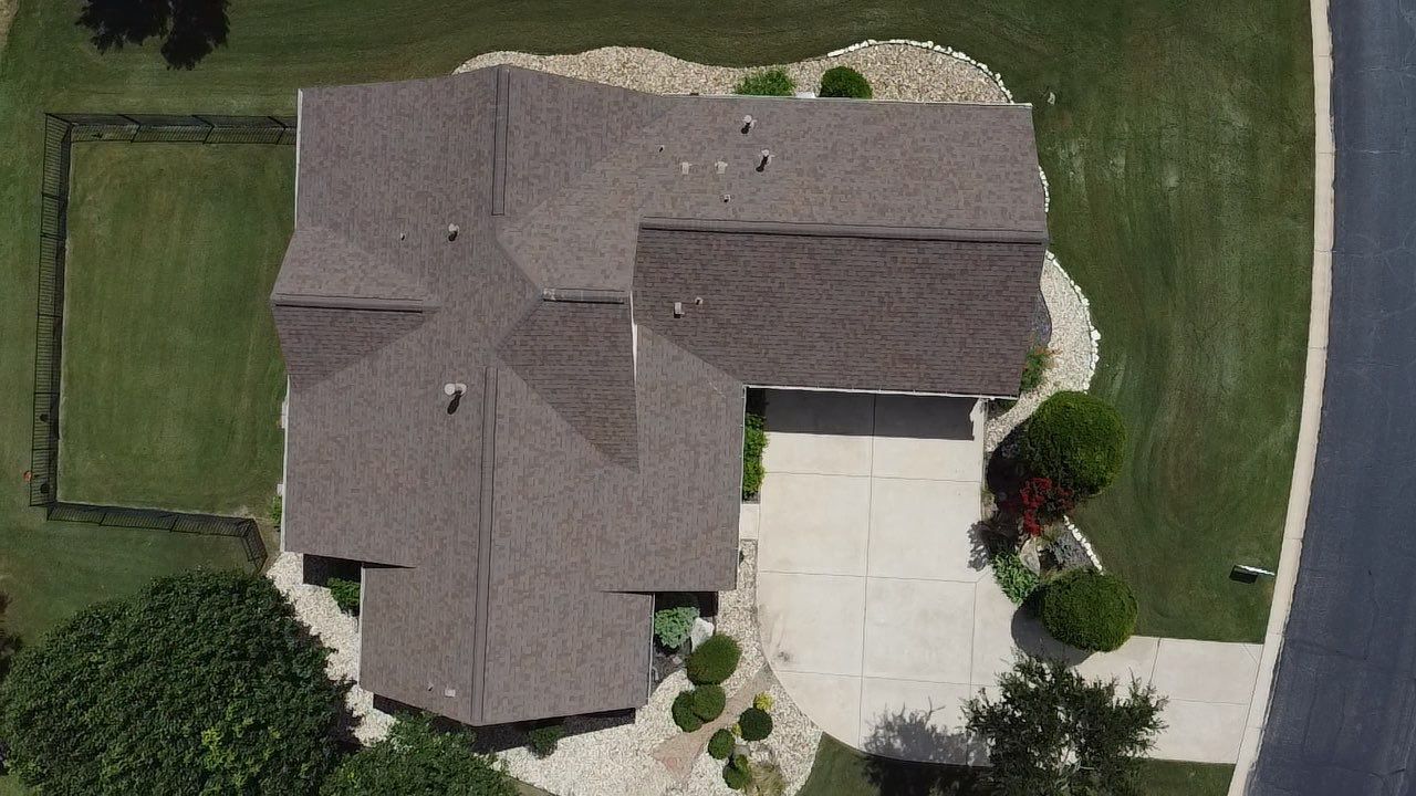 An aerial view of a house with a roof and a driveway.