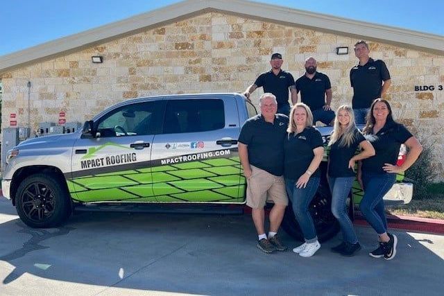 A group of people are posing for a picture in front of a truck.