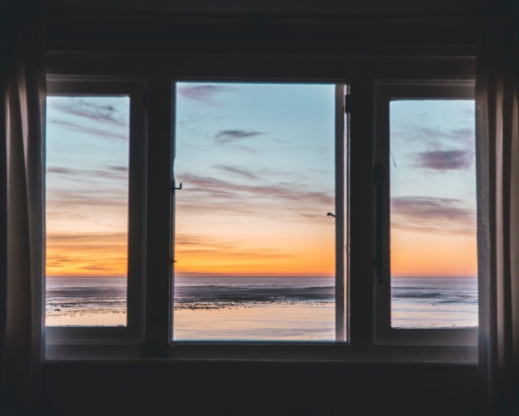 Sunrise over the ocean framed by three dark window panes