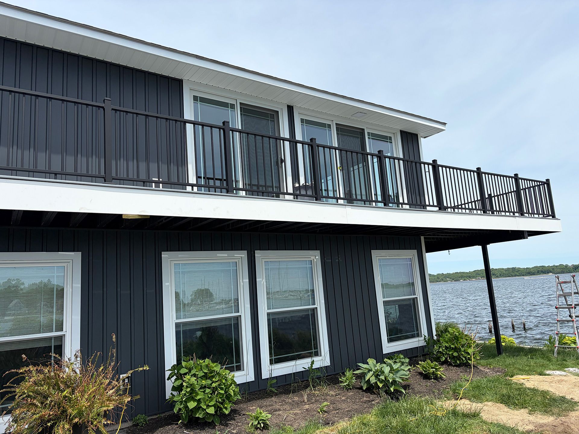 Modern dark house with black balcony overlooking the water