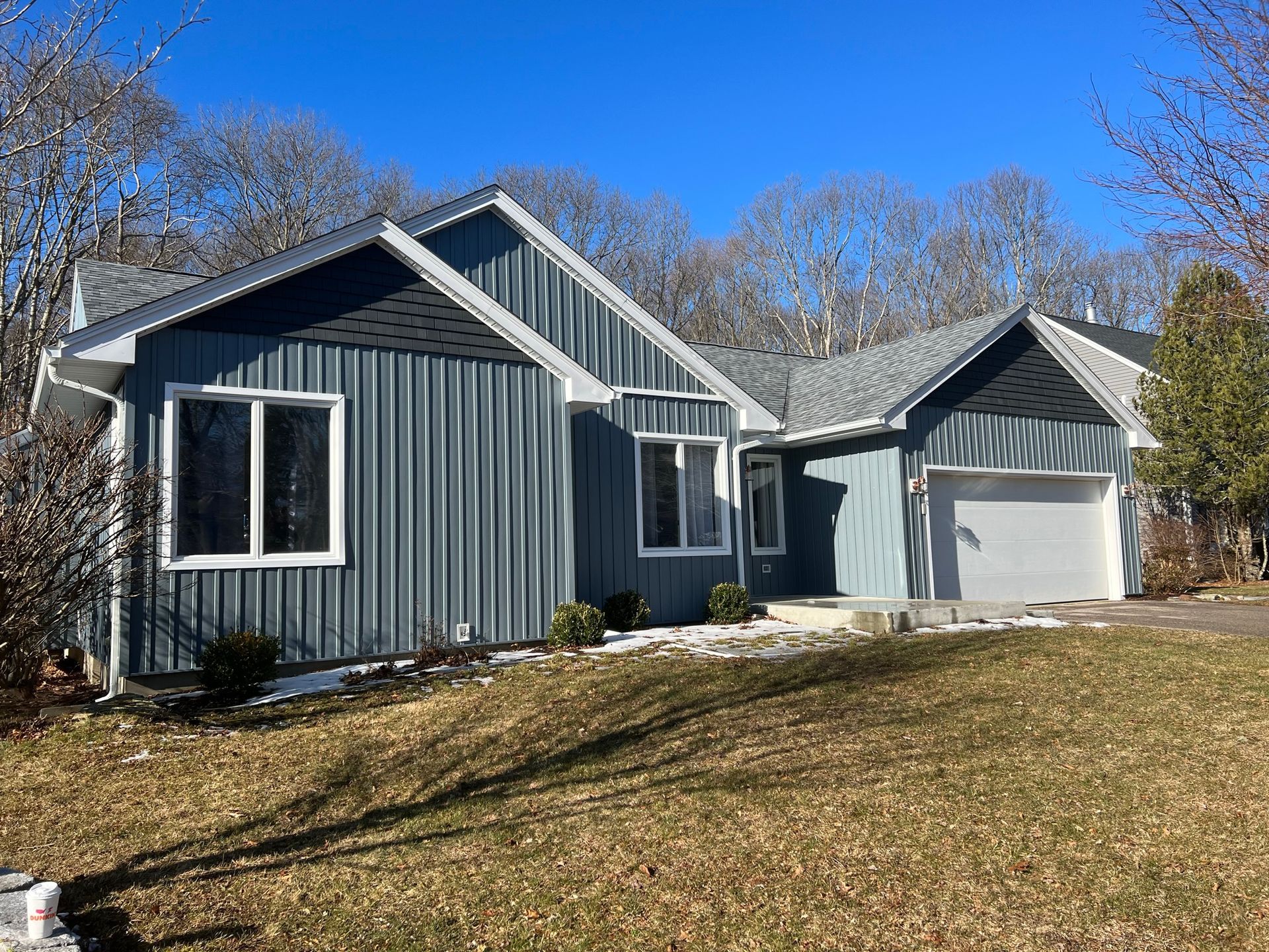 Gray house with white trim and attached garage under a clear blue sky