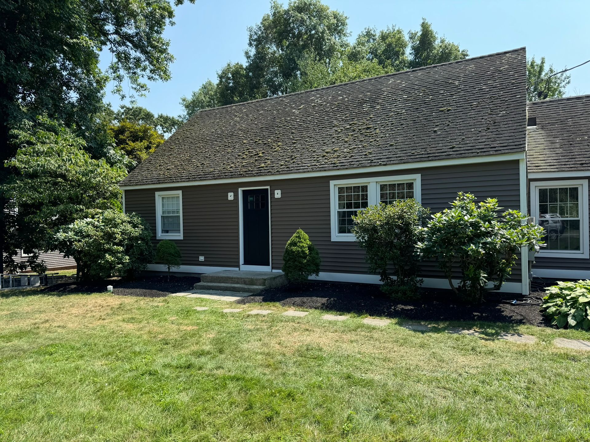 Single-story brown house with white trim and a front lawn on a sunny day