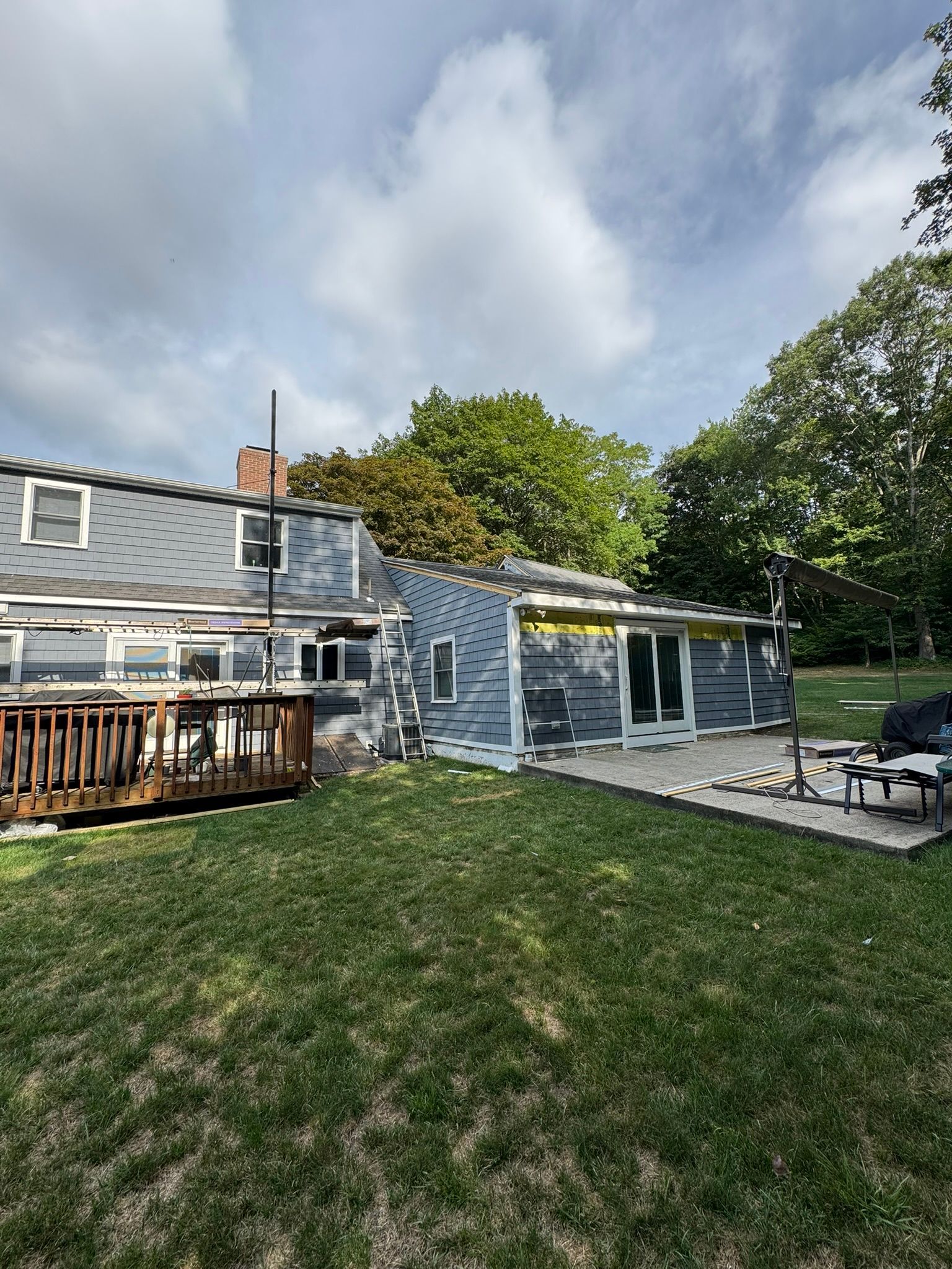 Backyard with stone patio, picnic table, and blue-gray house under a cloudy sky
