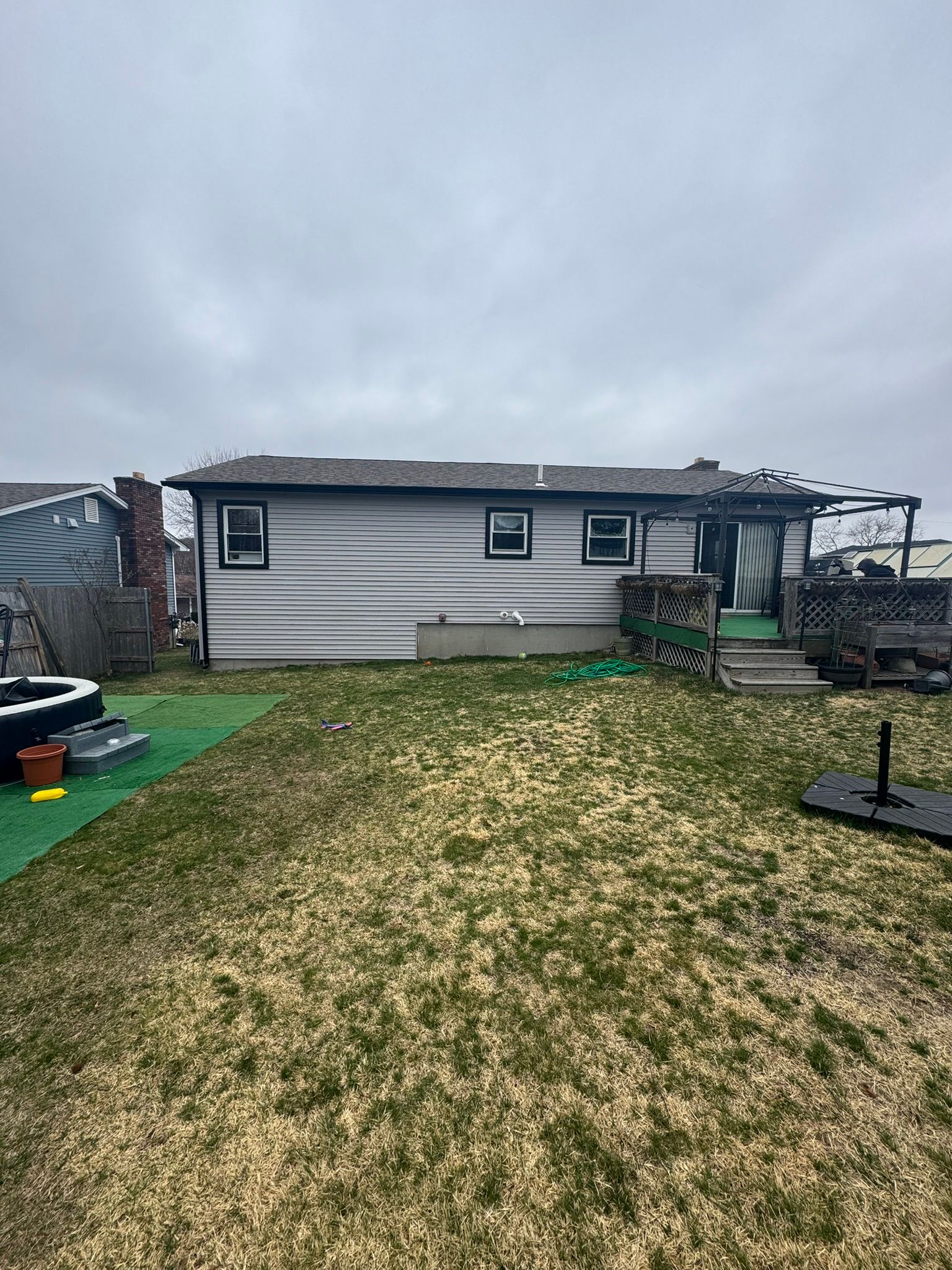 Backyard with a small white shed, cloudy sky, and patchy grass lawn.
