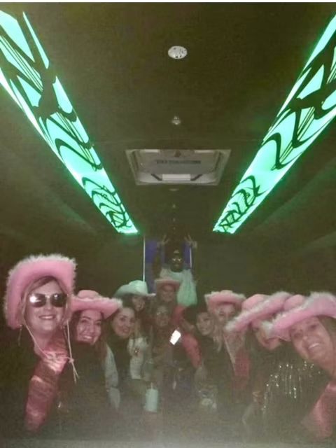 Group of women in pink cowboy hats, celebrating inside a limo with green lights.