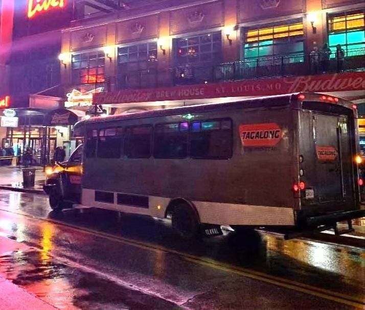 Tacky truck in front of a bar, wet street reflects lights.