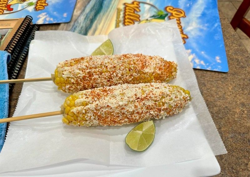 Two corn on the cob with lime wedges on a napkin