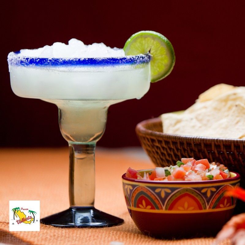 A margarita in a glass next to a bowl of salsa