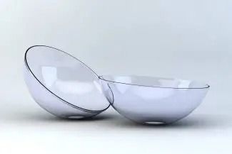 Two clear, glass-like contact lenses rest side-by-side against a plain, light background.