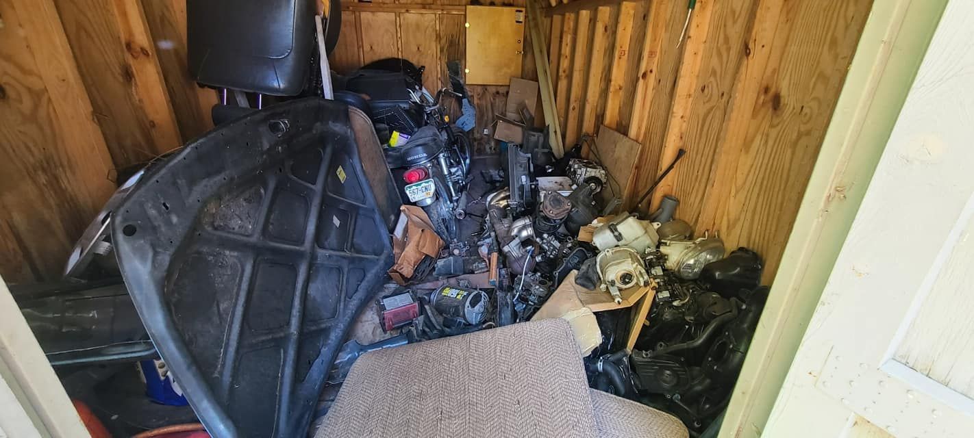 A cluttered storage shed filled with miscellaneous auto parts, plastic items, and scattered debris.