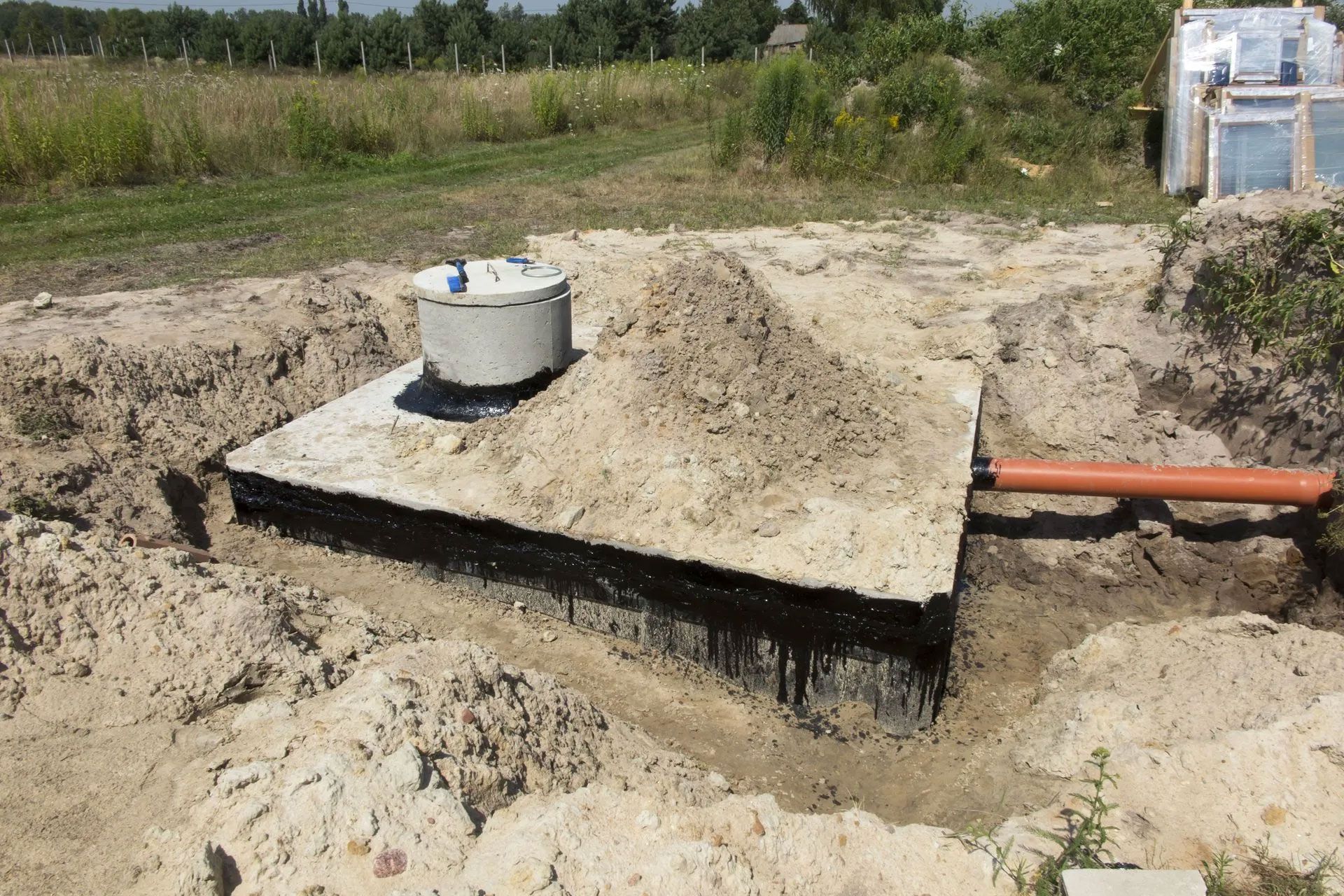 A septic tank is being built in a dirt field.