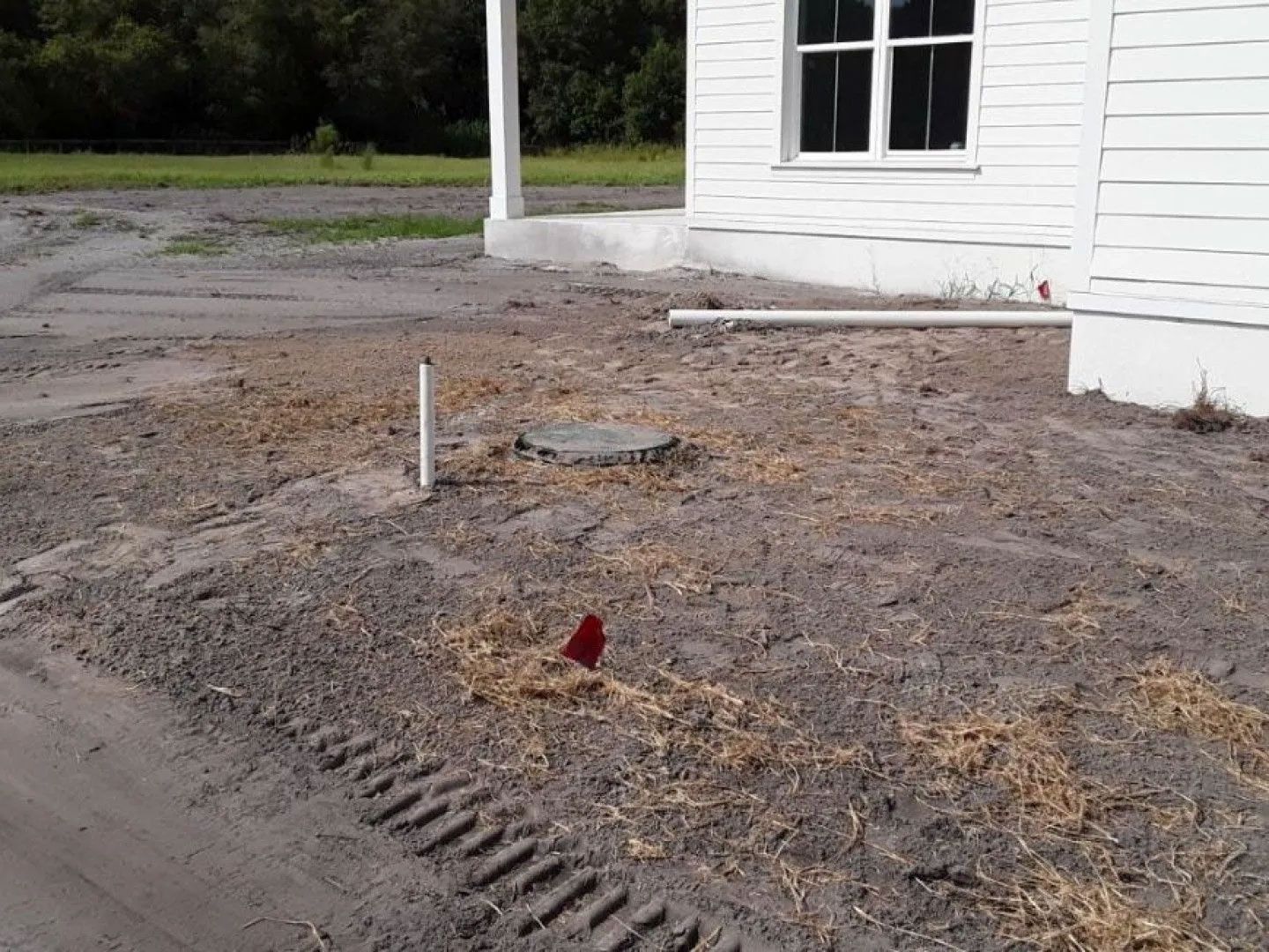 A white house is sitting in the middle of a dirt field.