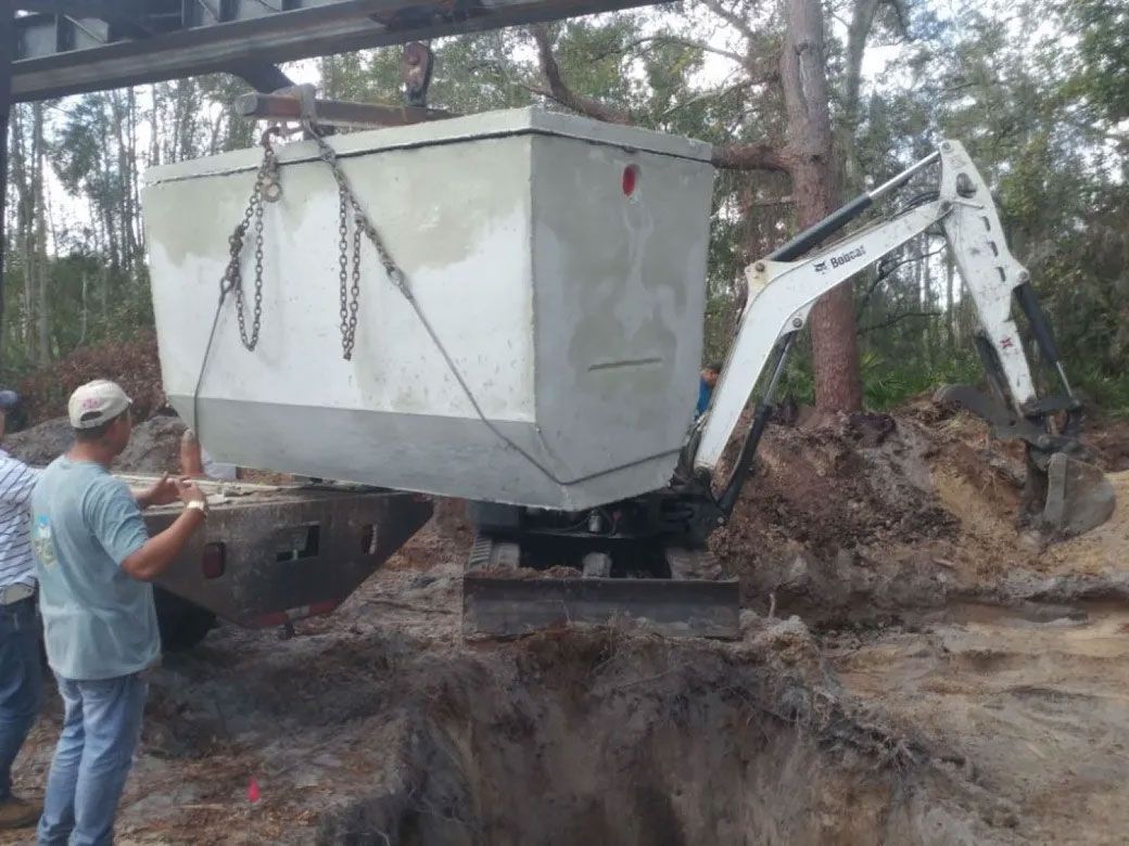 A man is standing next to a large white box being lifted by a bulldozer.