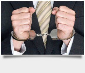 A man in a corporate suit handcuffed