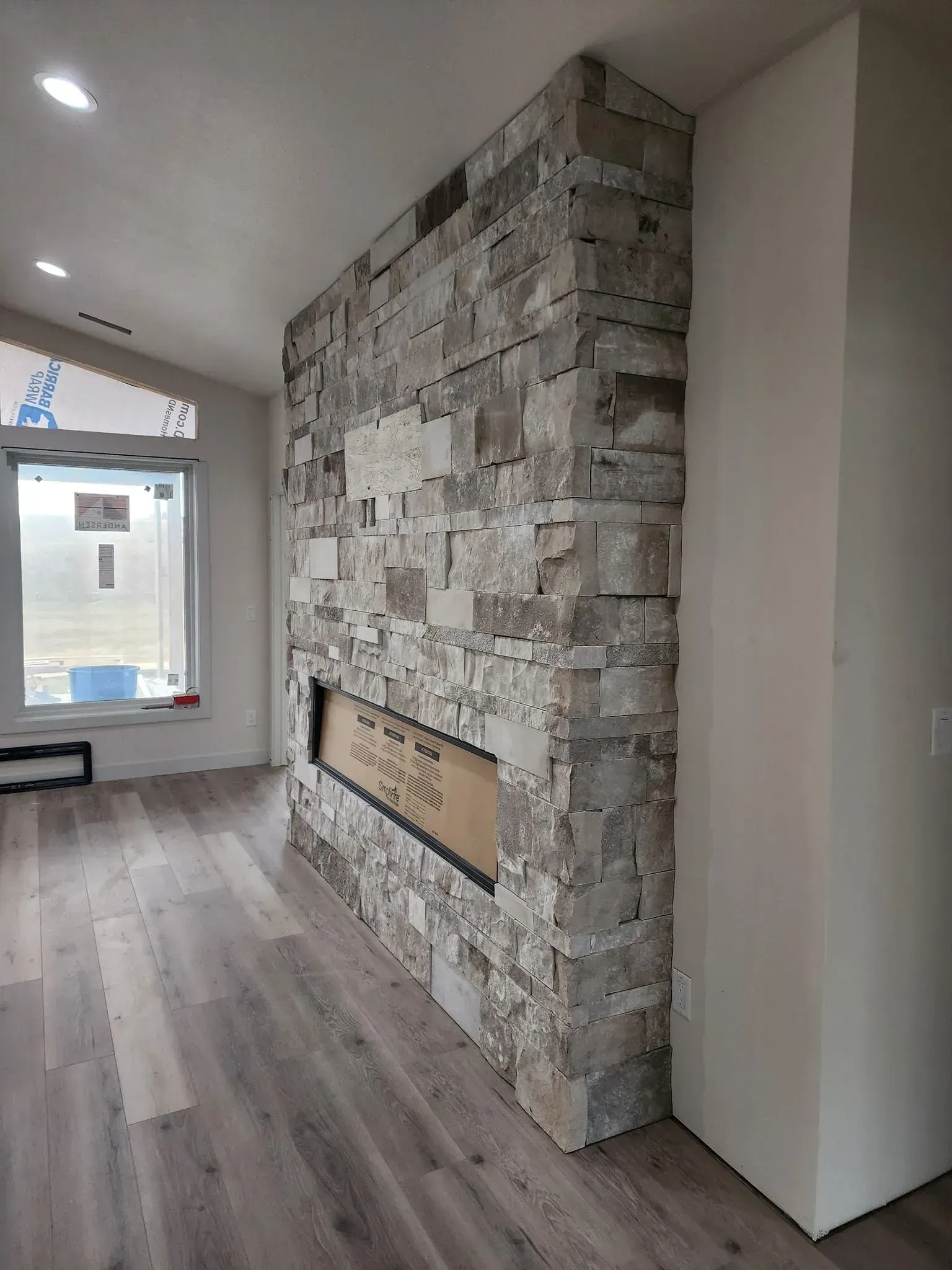 Stone fireplace with a built-in firebox in a modern room with wood-look flooring.