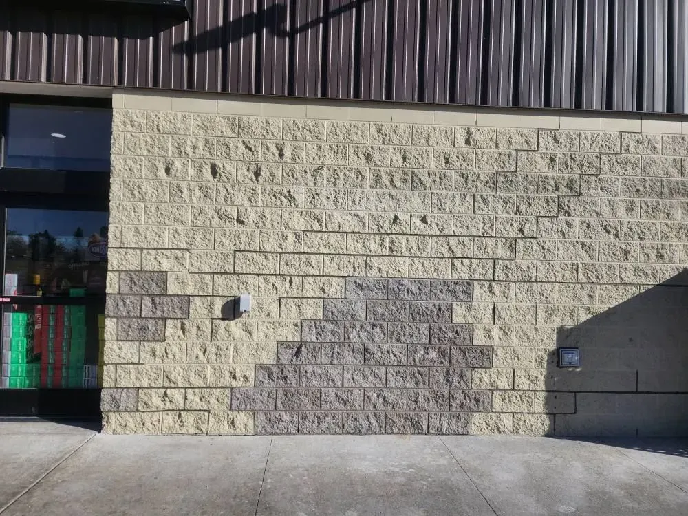 Exterior wall with light-colored bricks, a patch of darker bricks, and a doorway.